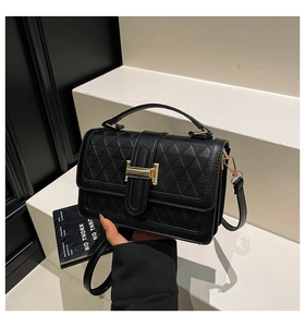 Detail of black textured PU leather handbag featuring 3D geometric patterns and gold buckle