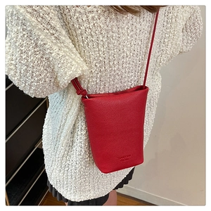 Detailansicht der roten Eimer-Tasche aus Lychee-Leder mit Logoprägung auf Strick