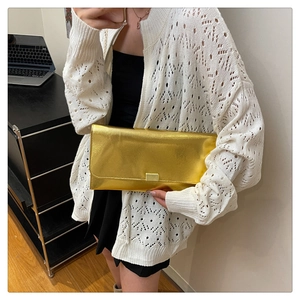 Close-up of a gold envelope-style crossbody bag with a square buckle lock detail