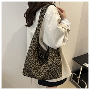 Detail shot of a stylish leopard print canvas hobo bag on a model's shoulder