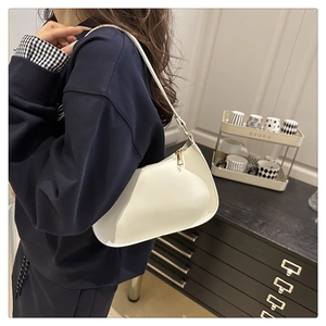 White minimalist underarm bag with smooth leather and gold zipper worn by a model
