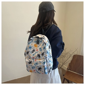 Détail d'imprimés tropicaux de palmiers et d'ananas sur un sac à dos blanc pour filles