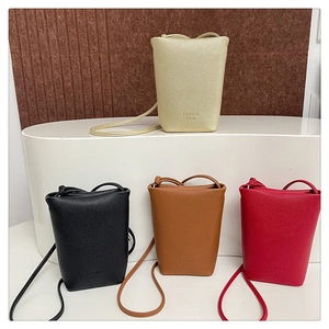 Mini-Beuteltaschen mit Lychee-Struktur in Gold, Schwarz, Braun und Rot auf weißen Podesten