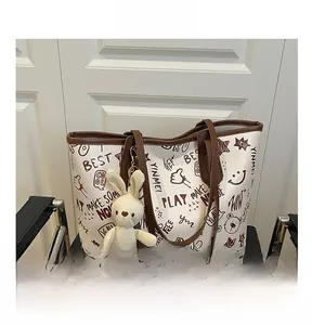 Détail du sac cabas blanc avec motifs graffiti marron et pendentif lapin mignon