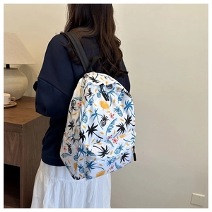 Close-up of lightweight white backpack with tropical palm and pineapple patterns on back