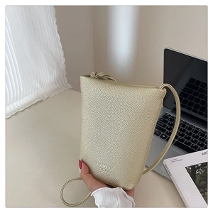 Nahaufnahme der champagnergoldenen Handytasche aus Leder mit feiner Lychee-Narbung