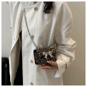 Detail of leopard print crossbody bag with silver metal bow and delicate chain strap