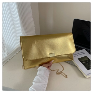 Close-up of golden metallic cross-grain envelope bag with square metal buckle and chain