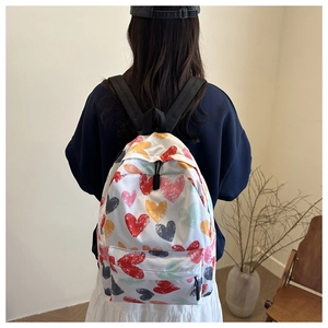 Detail view of stylish white backpack with colorful heart graffiti patterns on model