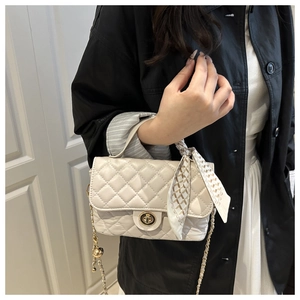 Detail of beige quilted leather handbag with metal turn-lock and silk scarf handle