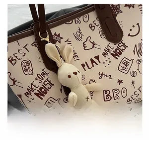 Détail du cabas en cuir crème avec imprimés graffiti et breloque lapin en peluche