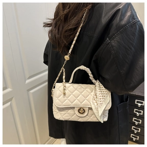 Detail of beige quilted handbag with gold lock and silk scarf handle on model