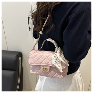 Detailed shot of pink quilted crossbody bag with silk scarf handle and chain strap