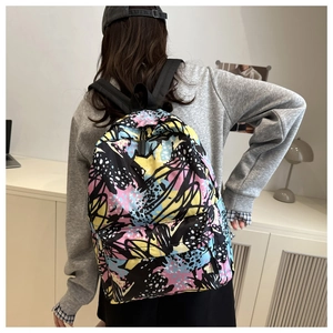Detail of canvas backpack with colorful abstract graffiti patterns and black textile straps