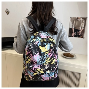 Colorful butterfly print backpack worn by a model in a cozy minimalist home setting