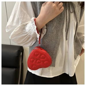 Dettaglio borsa rossa trapuntata a forma di cuore con cerniera in metallo e cinturino