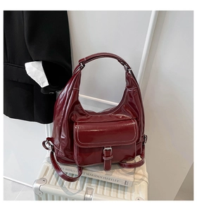 Detail of burgundy glossy hobo bag with contrast stitching and silver utility buckle