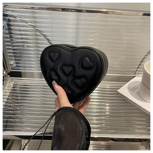 Detailed macro view of heart-shaped black leather bag with embossed 3D heart patterns