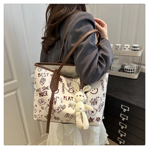 Détail du sac cabas en toile imprimée avec bordure en cuir et breloque lapin en peluche