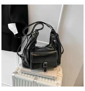 Detail of glossy black shoulder bag with contrast stitching and front buckle pocket