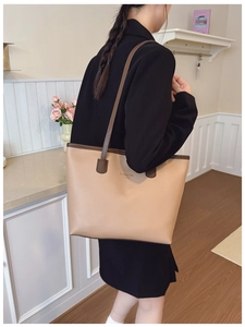 Modelo luciendo un gran bolso tote caqui con bordes en marrón oscuro para estilo otoño