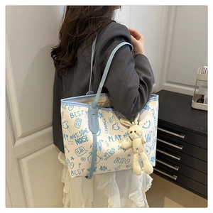 Détail du sac cabas graffiti blanc avec anses bleues et breloque lapin en peluche doux