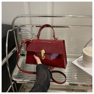 Detail of burgundy patent leather bag with gold twist lock and glossy finish