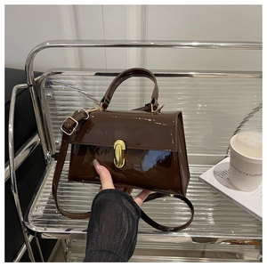 Detailed close-up of dark brown patent leather handbag with elegant gold metal twist lock