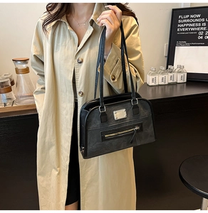 Detail of minimalist black matte hobo bag with silver hardware on a beige trench coat