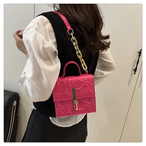 Detail of fuchsia embossed square bag with gold metallic buckle and chain strap