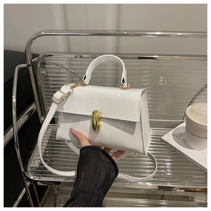 Detailed shot of white patent leather handbag with glossy finish and gold twist lock