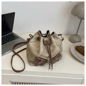 Detail of vintage canvas bucket bag with brown leather accents on a modern white desk