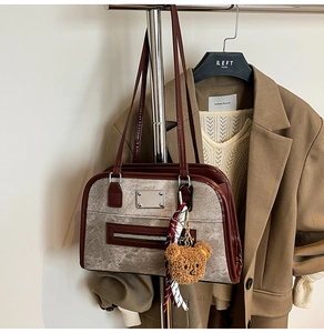 Detail of vintage canvas underarm bag with leather trim and cute teddy bear pendant