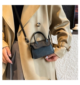 Vue détaillée du cuir grainé noir et des finitions dorées sur le mini sac à main chic