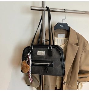 Close-up of black retro matte shoulder bag with a cute bear charm and silver hardware