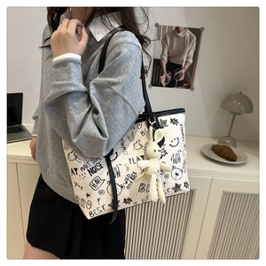 Détail du sac fourre-tout graffiti avec pendentif lapin et ordinateur portable sur bureau