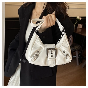 Détail du sac à bandoulière blanc plissé avec boucle métallique sur un blazer noir