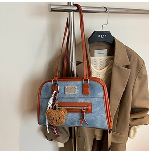 Detail of vintage denim underarm bag with leather trim and a cute plush bear charm