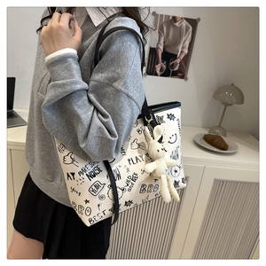 Détail d'un grand sac cabas blanc à motifs graffiti noirs et pendentif lapin peluche