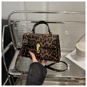 Detail of leopard print crossbody bag with gold twist lock and metallic finish