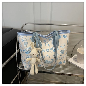 Détail du sac cabas imprimé avec gribouillis bleus et un adorable charme de lapin