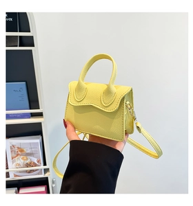 Détail du mini sac bandoulière jaune avec rabat ondulé et texture grainée