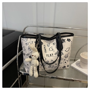 Détail du sac cabas blanc avec imprimé graffiti noir et pendentif lapin en peluche