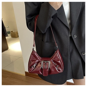 Macro shot of glossy burgundy leather bag with silver metal buckle and buckle straps