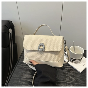 Détail du sac beige montrant la texture tissée et la boucle en métal argenté en forme de D