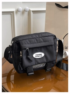 Detail view of black canvas crossbody bag featuring utility buckles and zipper compartments