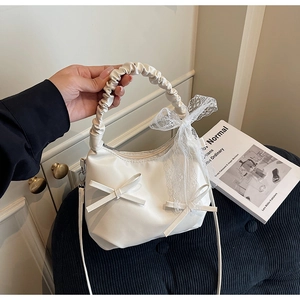 Détail du sac blanc crème avec ruban en dentelle et poignée froncée élégante
