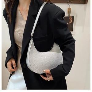 Close-up of silver crescent hobo bag with textured finish on a model wearing a black blazer