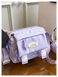 Detail of purple canvas messenger bag featuring plastic buckles and multiple zip pockets