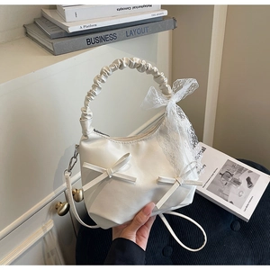 Détail de la poignée froncée et du grand nœud en dentelle sur ce sac à main blanc chic